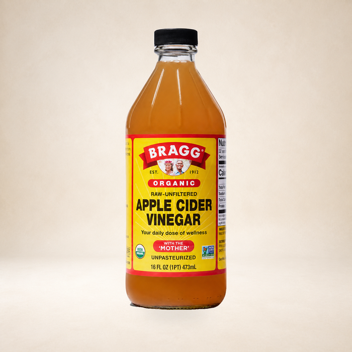 Bragg Apple Cider Vinegar 473ml on a warm studio background